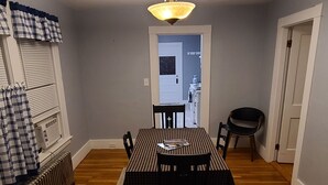 Une salle à manger avec une table dressée pour quatre personnes, un radiateur et un luminaire au plafond.