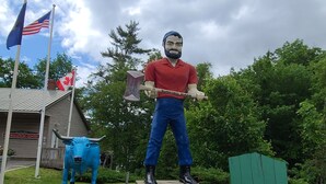 Une statue représentant un homme tenant une hache, située dans un parc, avec une plaque indiquant « Rumford, Maine ».