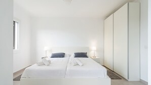A modern bedroom with a large bed, bedside tables, and a wardrobe.