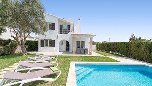 A modern two-story house with a swimming pool, outdoor seating, and a well-maintained garden.