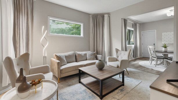 Ein modernes Wohnzimmer mit einer Couch, Sesseln, einem Couchtisch und einem Essbereich mit Tisch und Stühlen.