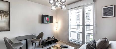 Una sala de estar moderna con un sofá, una mesa de comedor y un televisor.