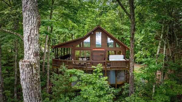 A wooden cabin with a balcony, surrounded by dense forest. - Mountain Views! Private Cabin, Firepit & Hot Tub, Fireplace--Dog Friendly! (Cherry Log)