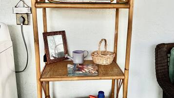 Ein mehrstufiges Bambusregal mit verschiedenen Gegenständen, darunter ein gerahmtes Bild, eine Tasse, ein Korb und Reinigungsmittel.