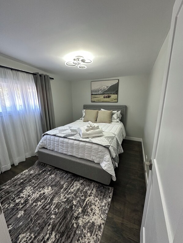 A modern bedroom with a bed, a rug, and a painting on the wall.