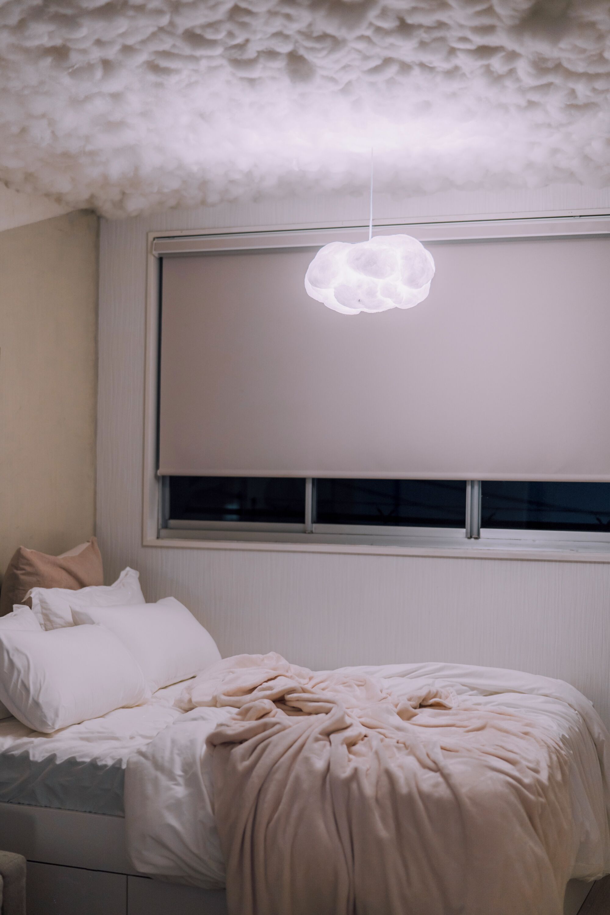 A bedroom with a bed, a window with a white blind, and a textured ceiling.