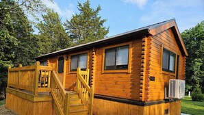 A log cabin with a wooden deck, a staircase, and a small air conditioning unit. - Walnut Secluded Cabin at Lost Trails (Madison Township)