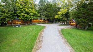 Un chalet avec une allée de gravier menant à une cabane en bois portant l’inscription « Maple » et à une autre cabane portant l’inscription « Cedar ».