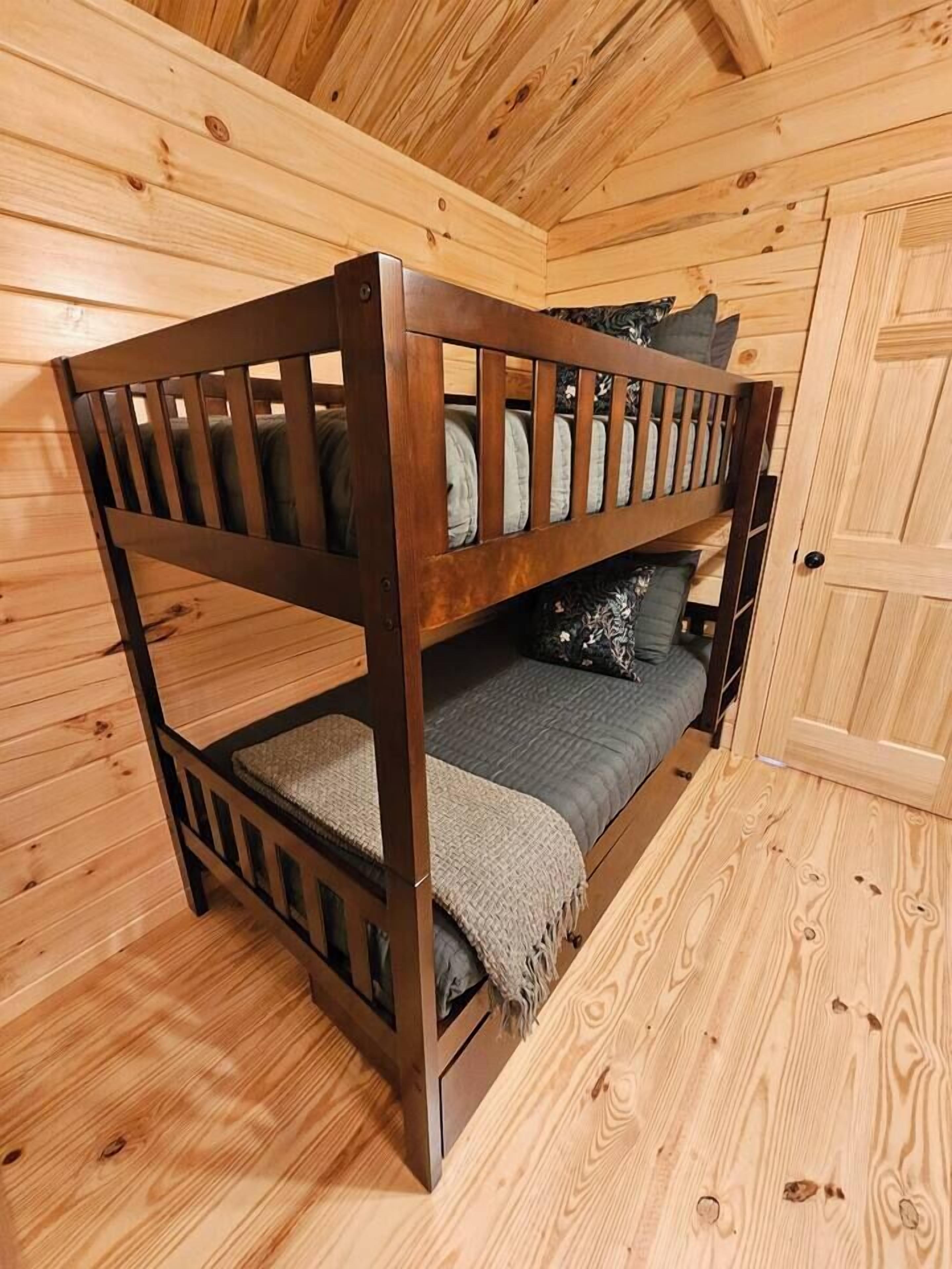 A bunk bed in a wooden cabin room with a door and a window.
