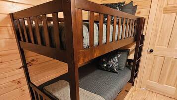 A bunk bed in a wooden cabin room with a door and a window.