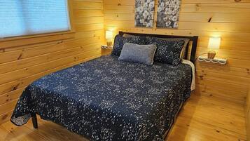 Een kamer met houten lambrisering, een bed, twee wandlampen en een raam met zonwering.