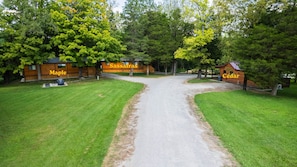 A lodge with a gravel driveway leading to a wooden cabin labeled 'Maple' and another labeled 'Cedar'. - Sassafras Woodland Cabin at Lost Trails (Madison Township)