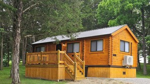 A log cabin with a wooden deck and stairs leading to a covered porch.
