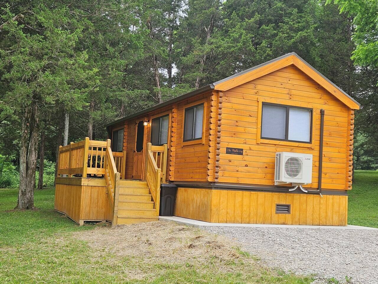 Una cabana de fusta amb un porxo, una escala i un aparell d'aire condicionat.