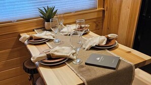 A wooden dining table set with plates, glasses, and a notebook.