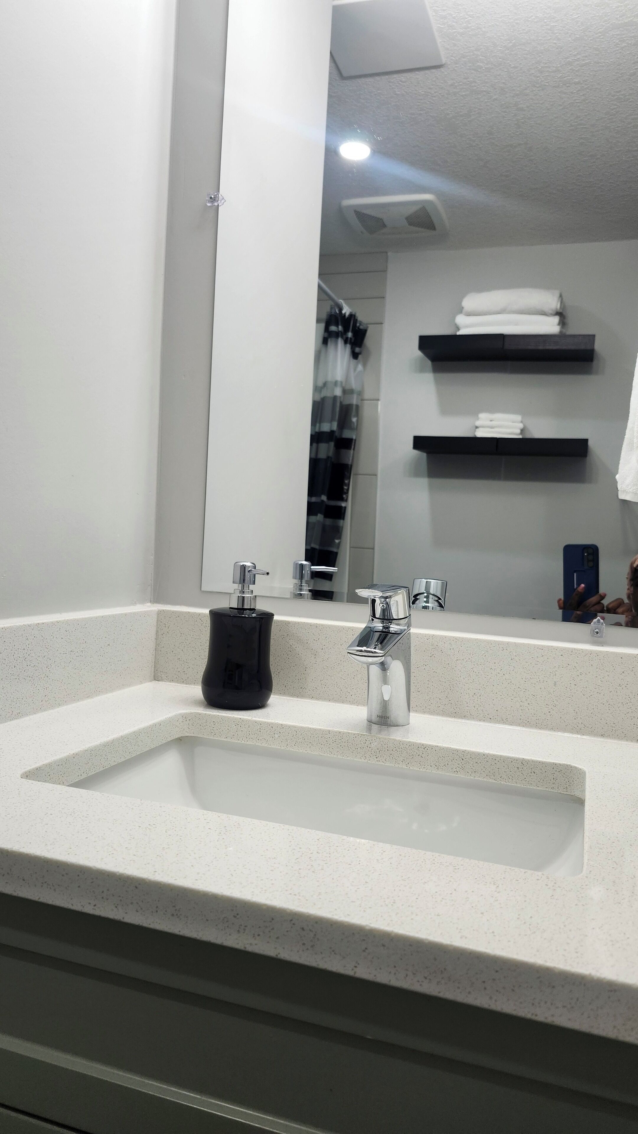 A bathroom with a large sink, a mirror, and a towel rack.