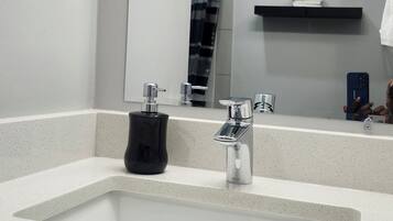 A bathroom with a large sink, a mirror, and a towel rack.