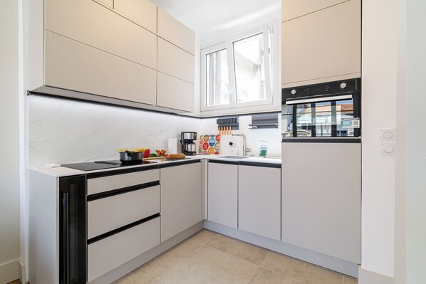 A modern kitchen with white cabinets, a black countertop, and a window above the sink.