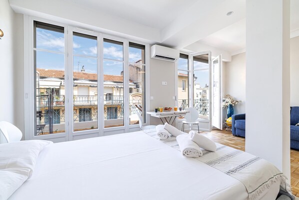 A hotel room with a large bed, a dining table, and a view of the cityscape.