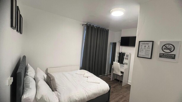 A modern bedroom with a bed, bedside table, and a TV mounted on the wall.