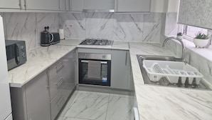 A modern kitchen with a built-in oven, a microwave, a gas stove, and a sink with a drying mat.
