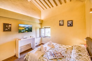 Un dormitorio con una cama, un escritorio, un televisor y cuadros en la pared.