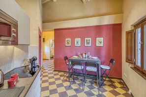 Cocina compacta con microondas, cafetera y piso de baldosas a cuadros.