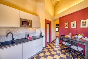 Una cocina moderna con piso a cuadros, un comedor con sillas y una pared de acento roja con cuadros enmarcados.