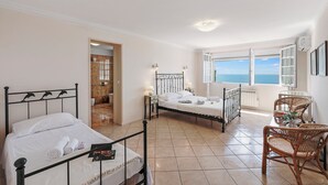 A bedroom with two beds, a balcony with a view, wicker chairs, and a small table with a vase. - Casa Del Sole - Sea view & Swimming pool, St Raphael, France (St Raphael)