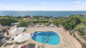 A pool with a stone patio, lounge chairs, umbrellas, and a view of the sea. - Casa Del Sole - Sea view & Swimming pool, St Raphael, France (St Raphael)
