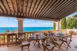 An outdoor dining area with a view of the sea, wooden furniture, and a covered pergola. - Casa Del Sole - Sea view & Swimming pool, St Raphael, France (St Raphael)