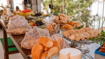 Uma mesa de buffet com diversos alimentos, incluindo pão, doces e frutas.