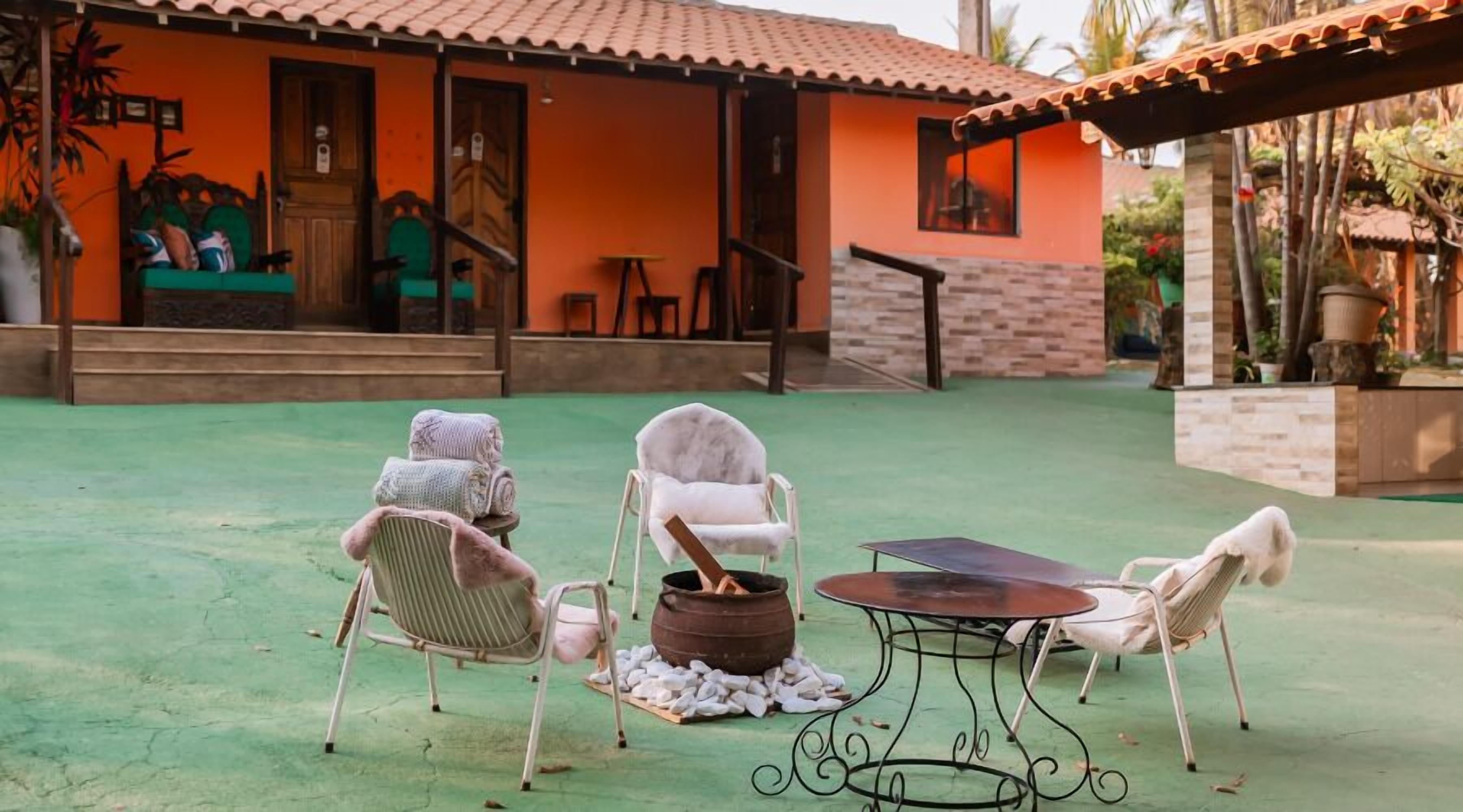 Un patio con dos sillas blancas, una mesa de metal y un estufa de leña.