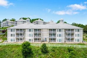 Ein mehrstöckiges Hotel mit flachem Dach, Balkonen und einem weißen Zaun im Vordergrund.