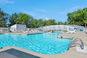 A swimming pool with multiple lanes, a white fence, and lounge chairs.