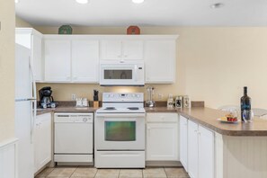 A kitchen with white cabinets, a microwave, a stove, and a coffee maker.