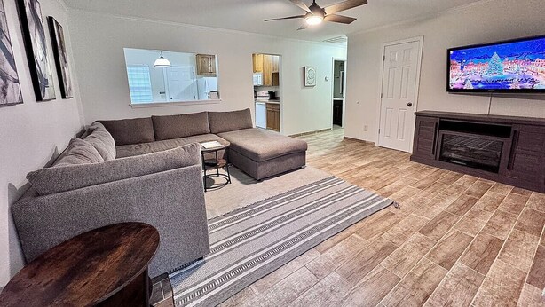 Ein Wohnzimmer mit Ecksofa, Couchtisch, Fernseher und Kamin.