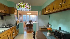 A kitchen with wooden cabinets, a dining table with chairs, a chandelier, and a microwave.