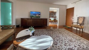 A living room with a television, a dining area with a chandelier, and a patterned rug.