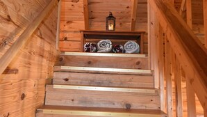 Una escalera de madera con un farolillo en la parte superior, que conduce a una habitación con techo de madera.