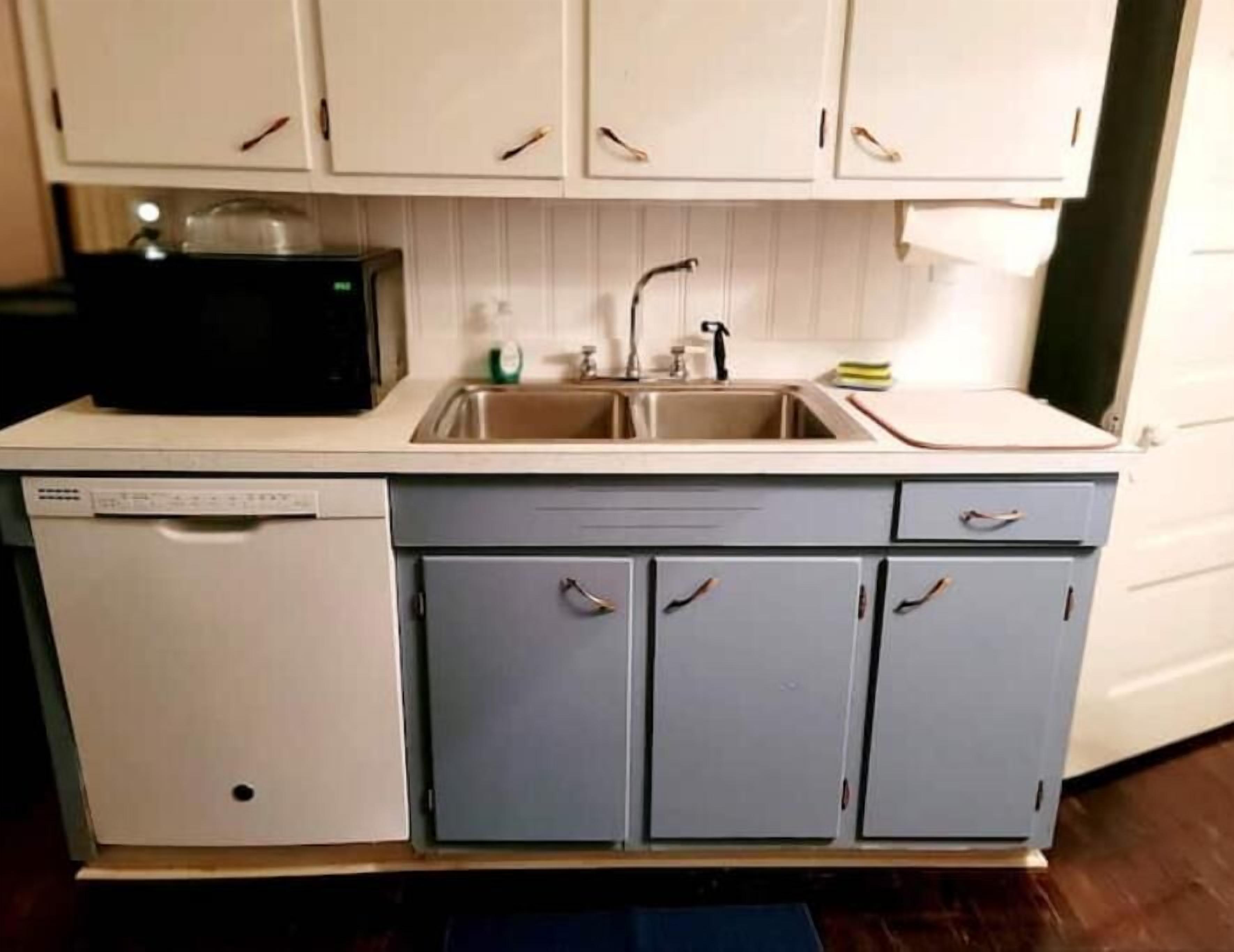 A compact kitchen with a dishwasher, a sink, and cabinets.