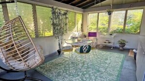 Una habitación soleada con una silla colgante, una mesita y un tapete de diseño verde.