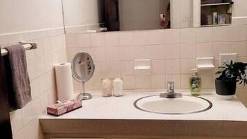 Un baño con lavamanos blanco, espejo y dos armarios con cajones.