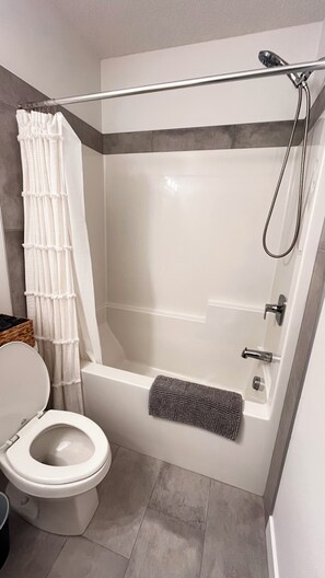 A modern bathroom with a shower, toilet, and a towel rack.