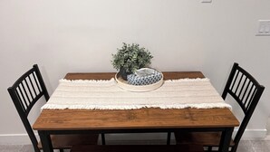 A dining table with a bench, two chairs, a potted plant, and a tissue box. - Modern Comfort | Private Guest Suite Getaway (Cochrane)