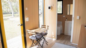 Habitació petita amb taula i cadires de fusta, una cuineta reduïda i vista a l'exterior.