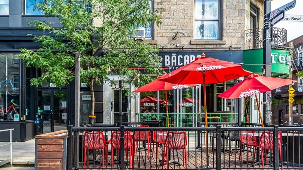An outdoor seating area with red chairs and umbrellas at a restaurant named BĂCARO. - Mont-Royal Apartment & Suite Near La Fontaine Park (Montreal)