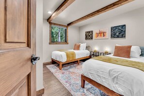 Een slaapkamer met twee bedden, een raam met uitzicht op bomen, en kunst aan de muur.