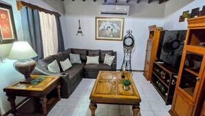 A living room with a sofa, a coffee table, a lamp, a clock, and a cabinet. - Cozy 3 bedroom House in Quepos center and near Manuel Antonio National Park (Quepos)