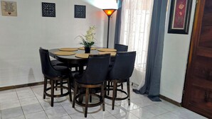A dining area with a round table, black chairs, and a potted plant. - Cozy 3 bedroom House in Quepos center and near Manuel Antonio National Park (Quepos)